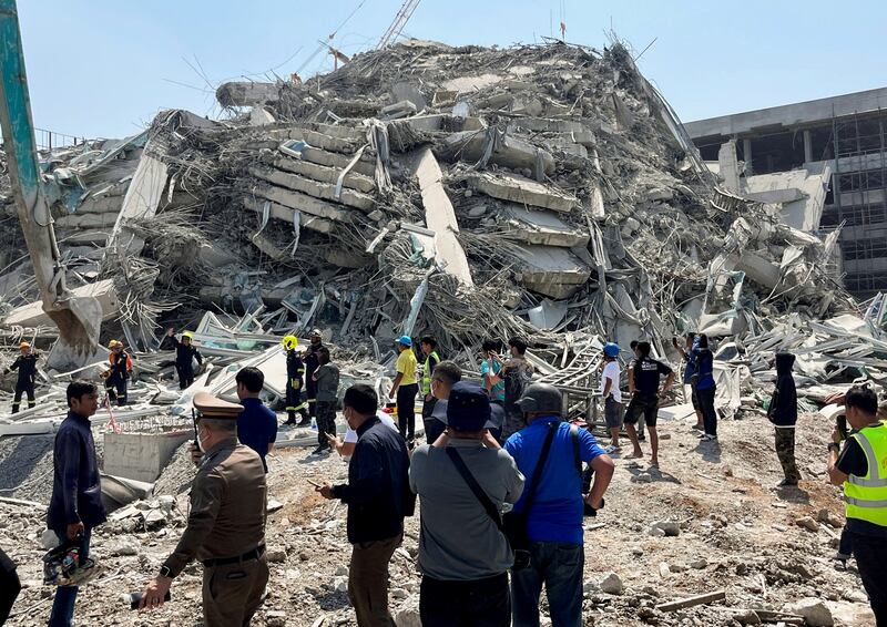 People stand at the site of a collapsed building in Bangkok after a strong earthquake struck central Myanmar, March 28, 2025.