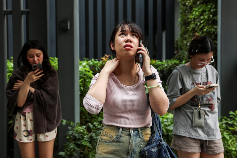 A woman in Bangkok stands outside a building after a strong earthquake struck central Myanmar, March 28, 2025.