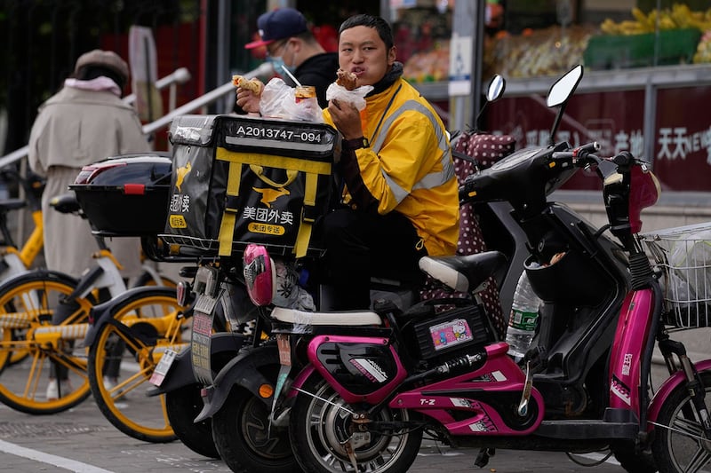 2021年10月10日,北京一名美团外卖员在坐在车上吃饭。(美联社)