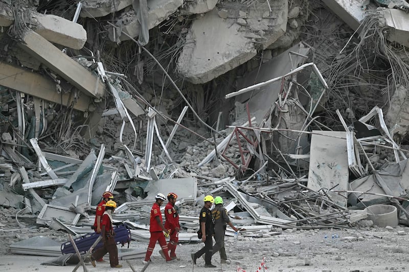 Rescue workers in Bangkok walk past the debris of a construction site after a building collapsed on March 28, 2025, following an earthquake in Myanmar.